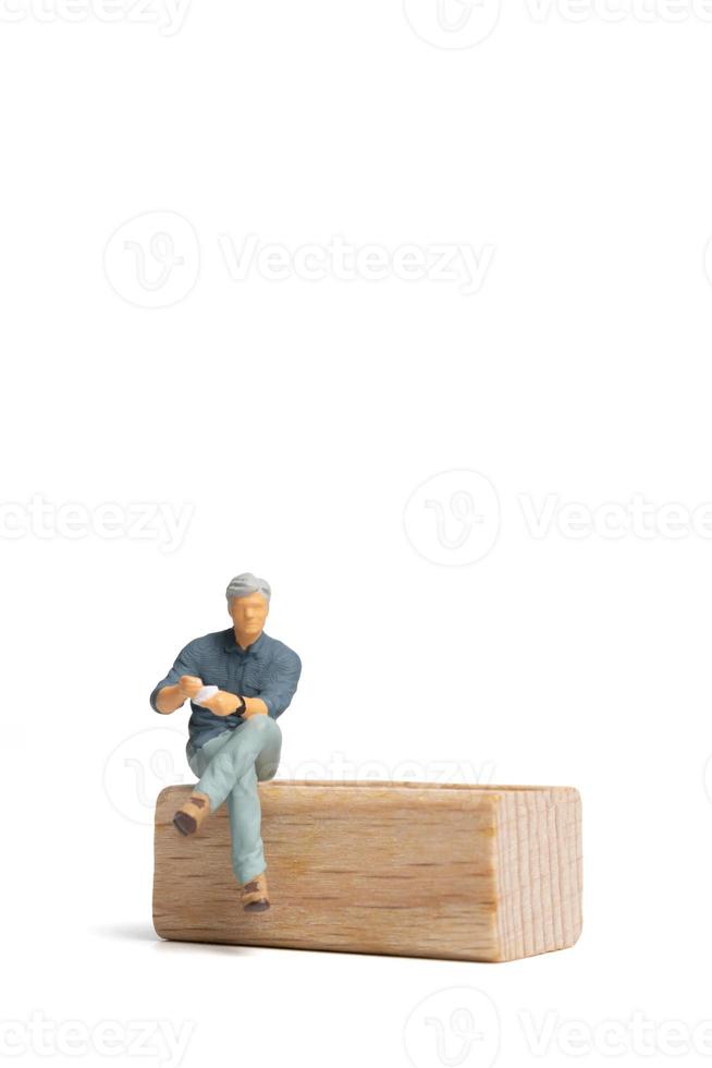 Miniature people Businessman sitting on wooden chair isolated on white background photo