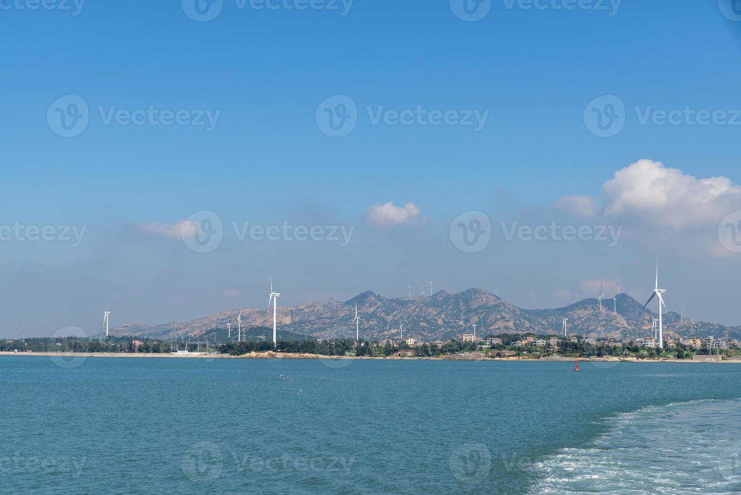 en la isla en medio del mar, muchas turbinas eólicas están instaladas bajo el cielo azul foto