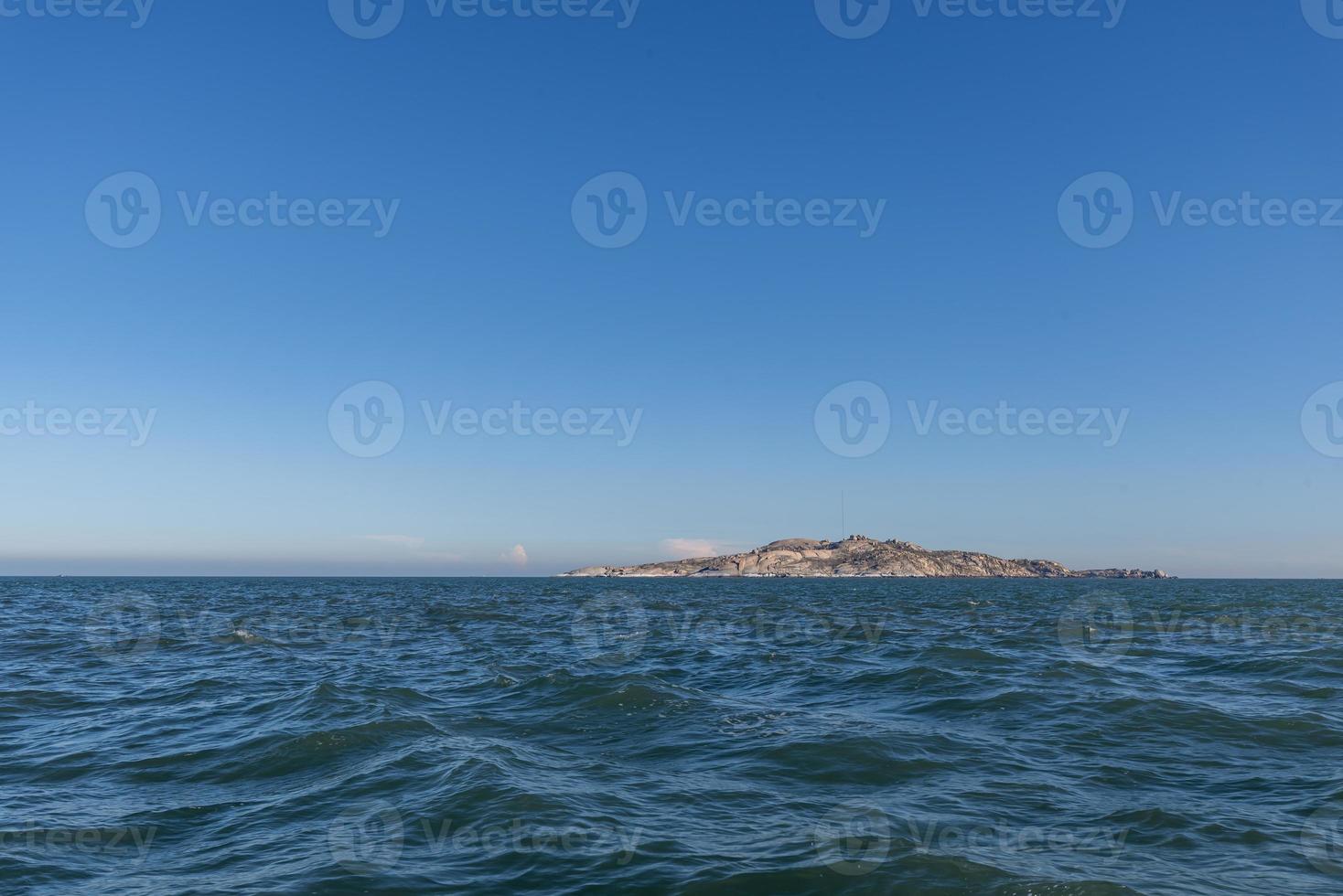 The sky is clear and blue, the island in the middle of the sea photo