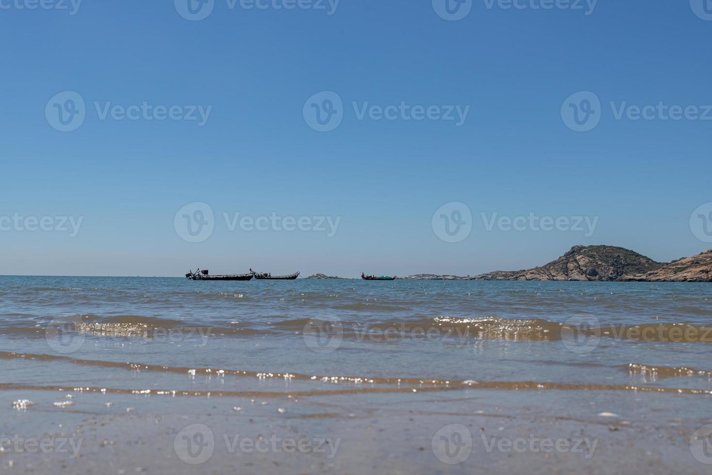 el mar bajo el cielo azul, playas limpias y agua de mar, así como islas y molinos de viento foto