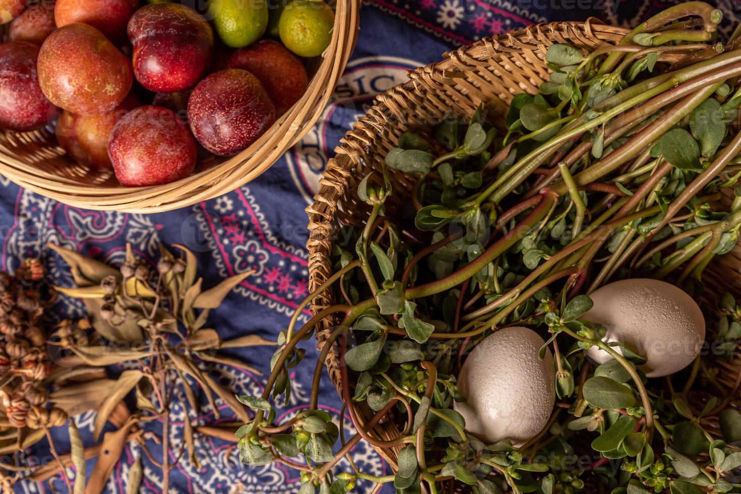 The eggs and other fruits and vegetables in the basket are on the wood grain table photo