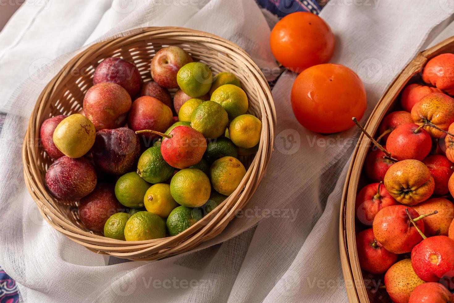 Many colors and varieties of fruit are either on the plate or scattered on the wooden table photo