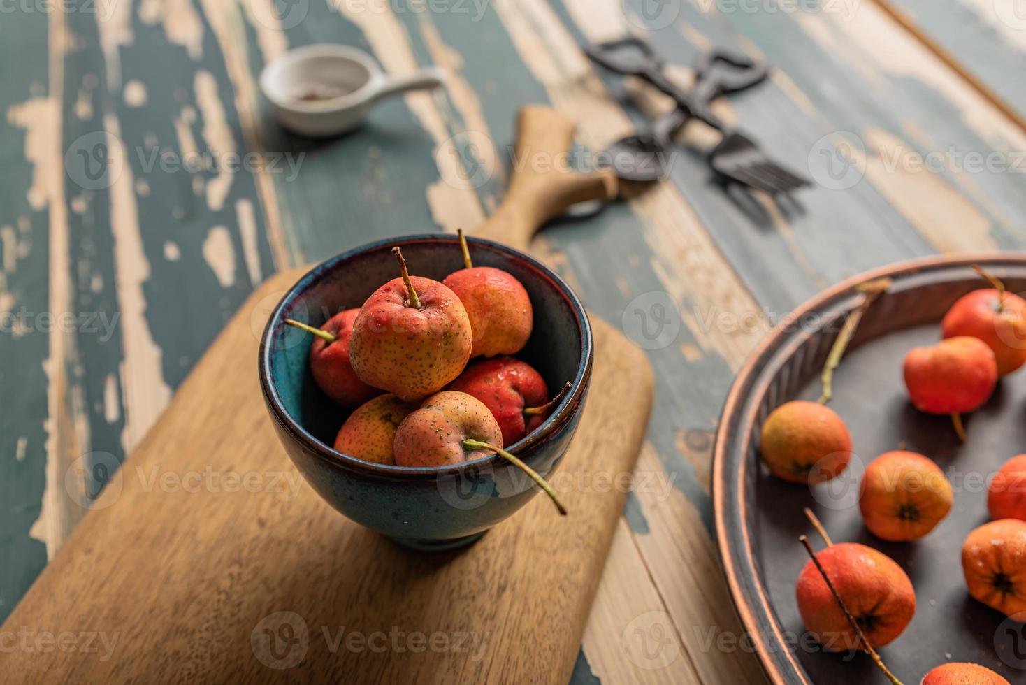 The red Hawthorn in the bowl is placed on the wooden table photo
