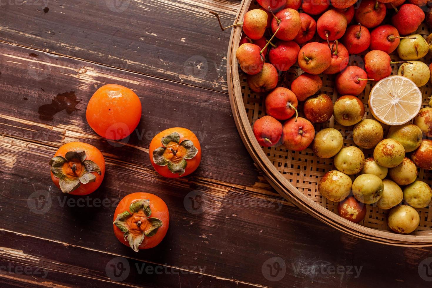 muchos colores y variedades de frutas están en el plato o esparcidas sobre la mesa de madera foto