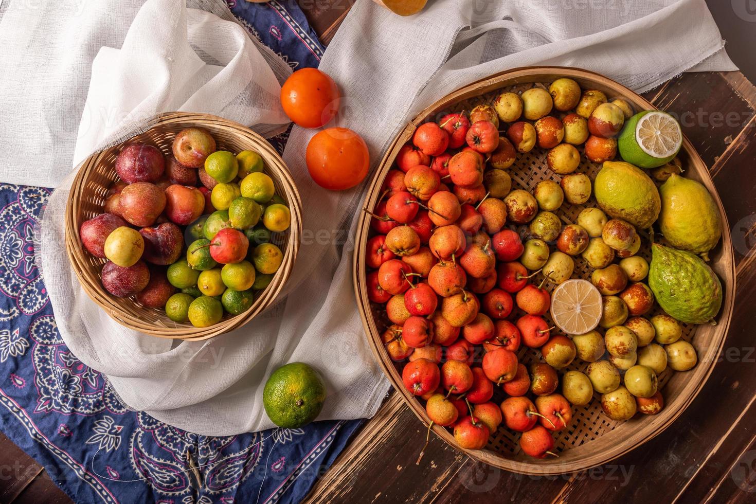 muchos colores y variedades de frutas están en el plato o esparcidas sobre la mesa de madera foto