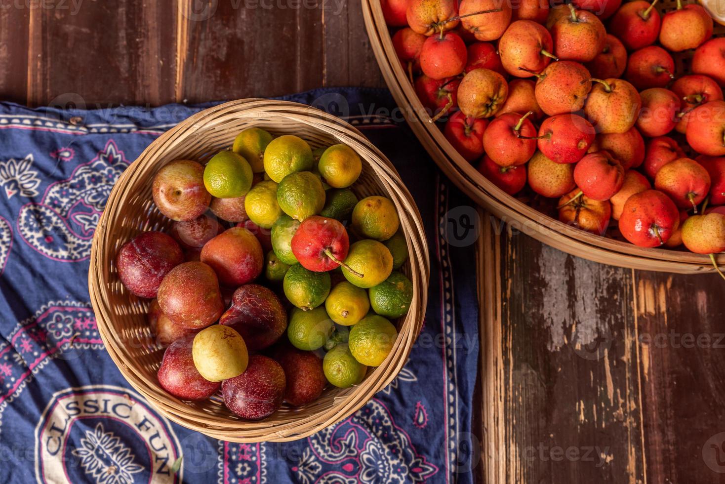 muchos colores y variedades de frutas están en el plato o esparcidas sobre la mesa de madera foto