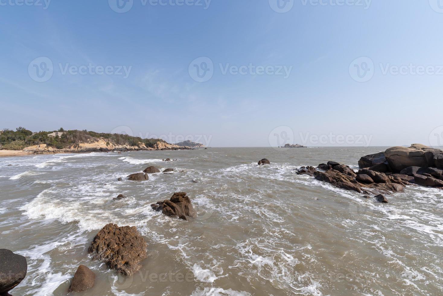 The white waves beat against the black rocks photo