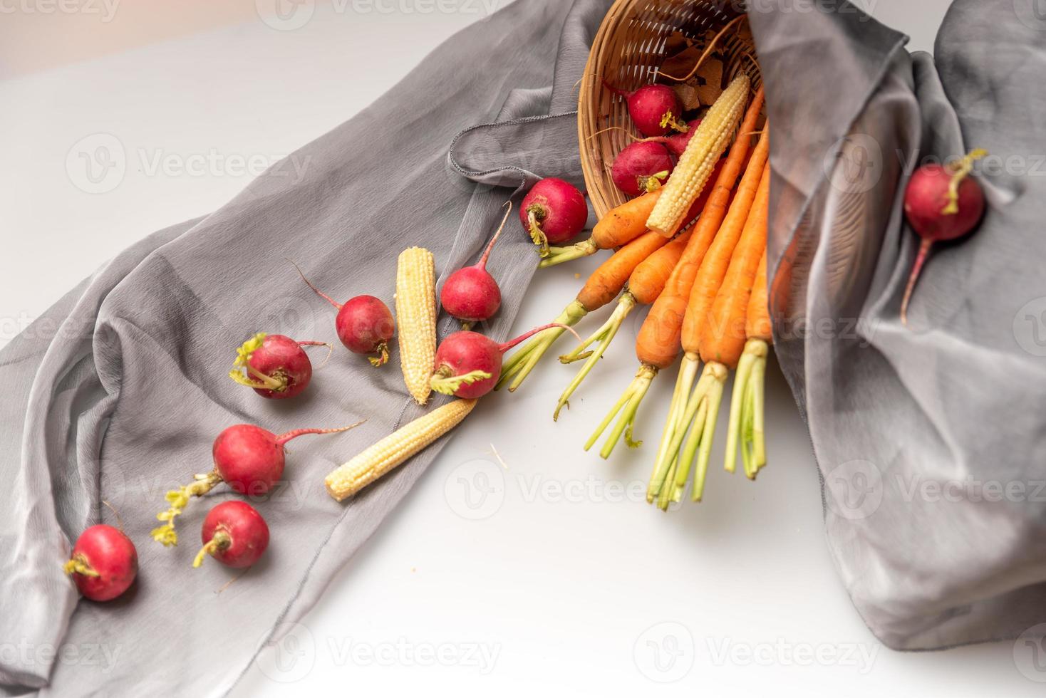 los rábanos rojos y naranjas están en la tela blanca foto