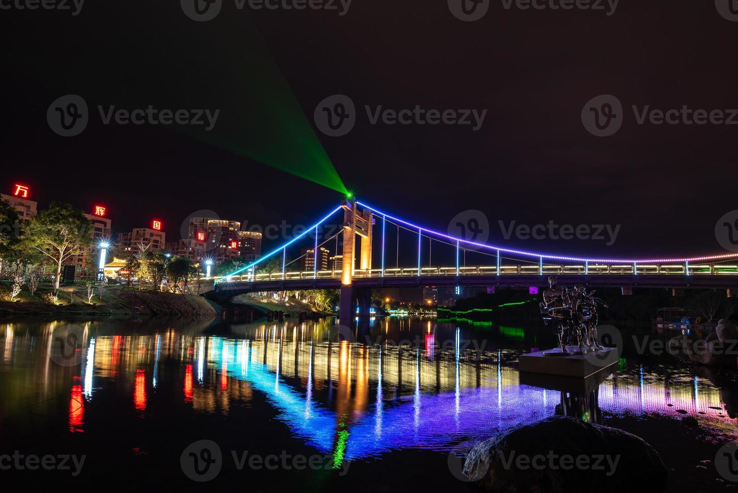 por la noche, el arroyo refleja las luces de colores en el puente foto