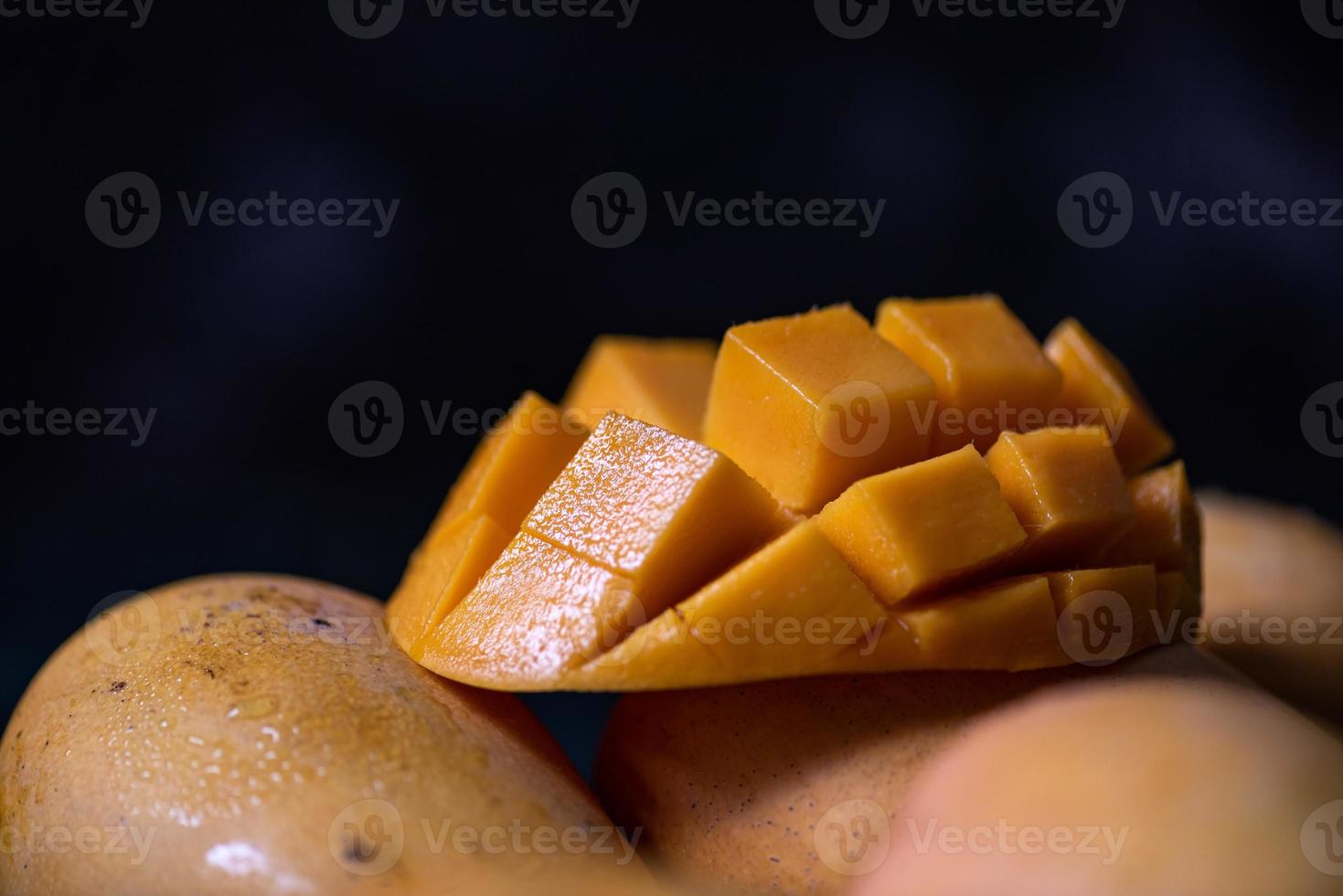 cortar y completar mangos en un plato en un ambiente oscuro foto