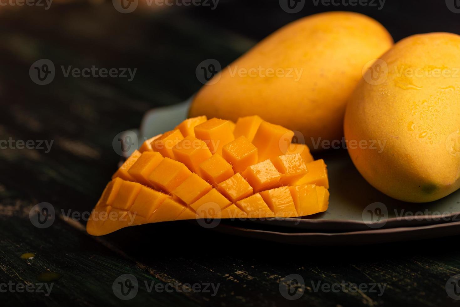 cortar y completar mangos en un plato en un ambiente oscuro foto