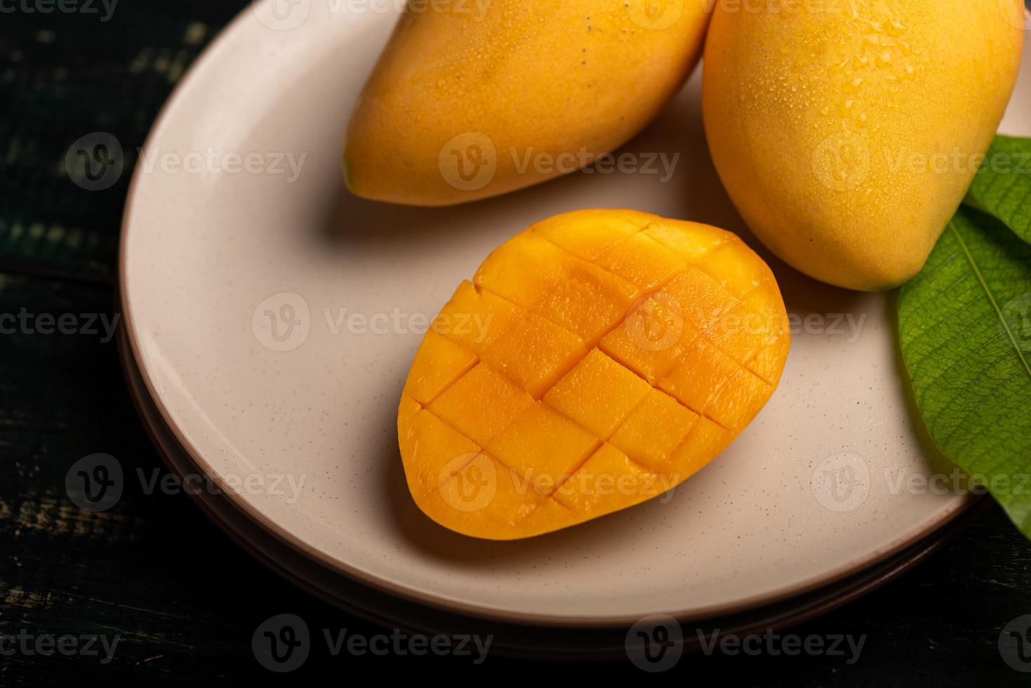 cortar y completar mangos en un plato en un ambiente oscuro foto