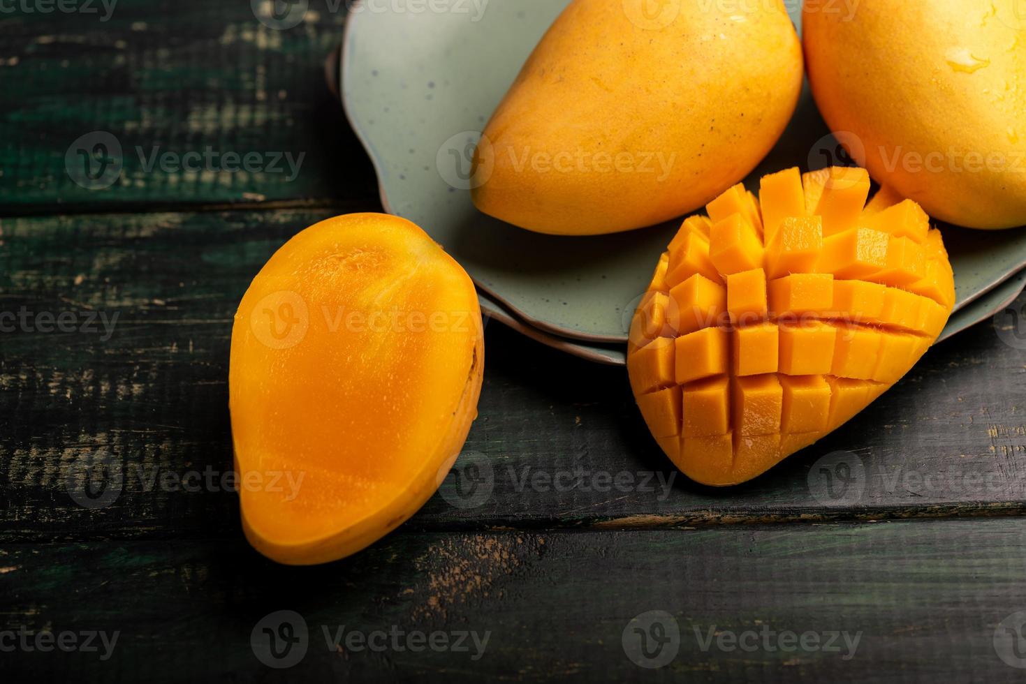 cortar y completar mangos en un plato en un ambiente oscuro foto