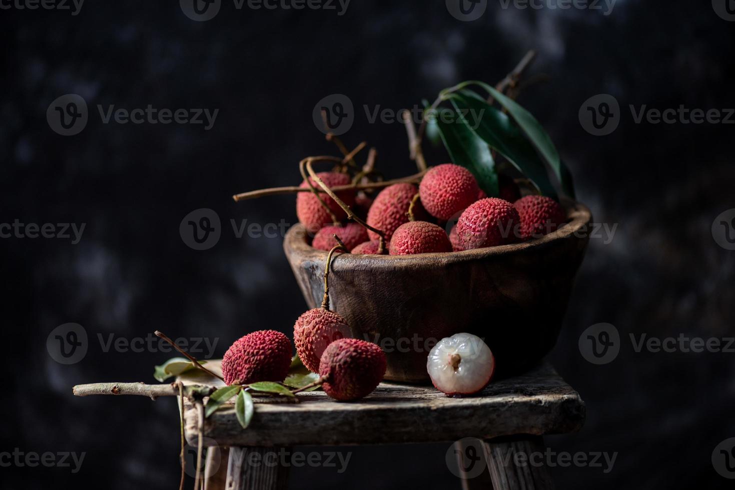 El litchi se coloca en un plato de madera, pelado o sin abrir, sobre una mesa de madera oscura. foto