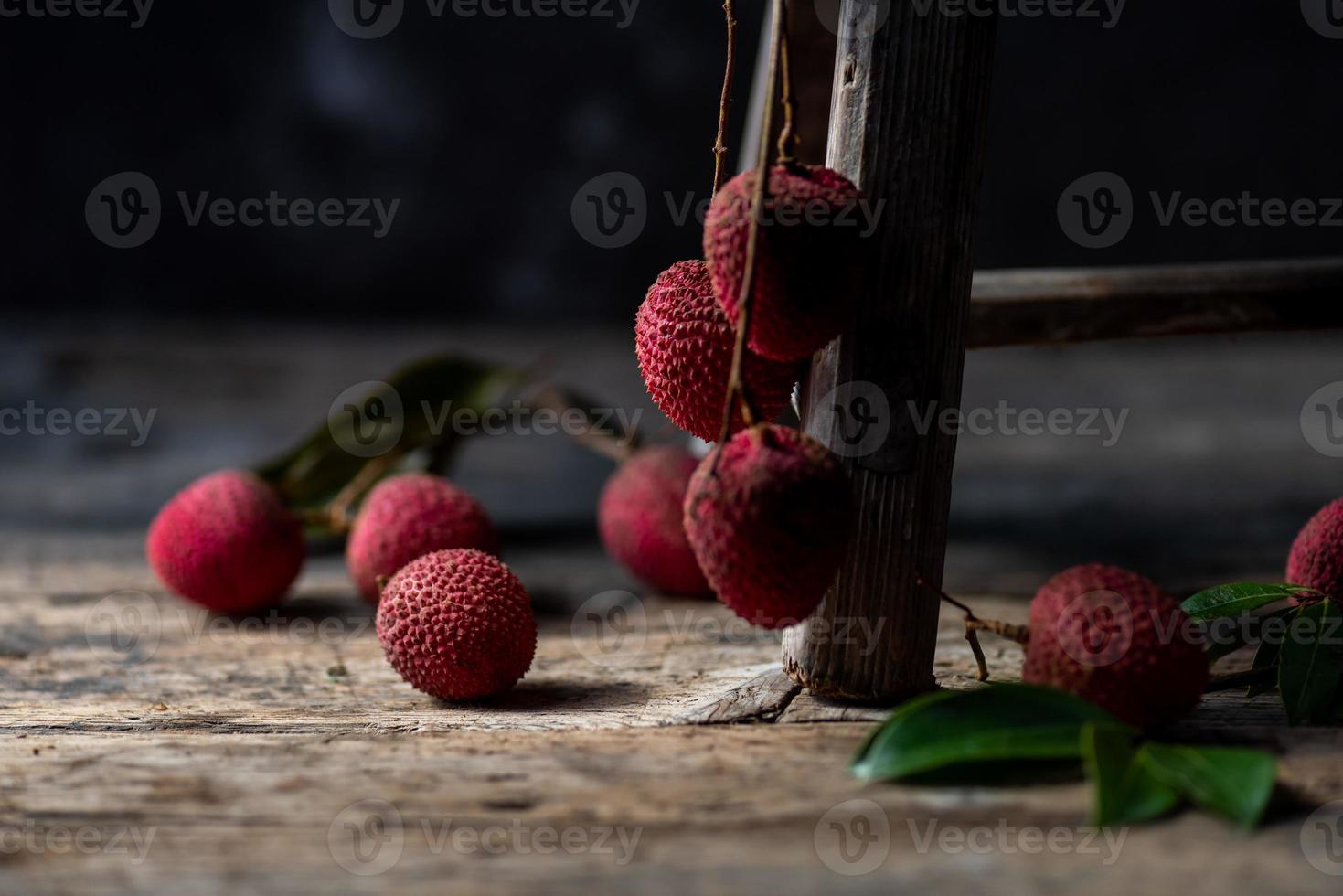 El litchi se coloca en un plato de madera, pelado o sin abrir, sobre una mesa de madera oscura. foto