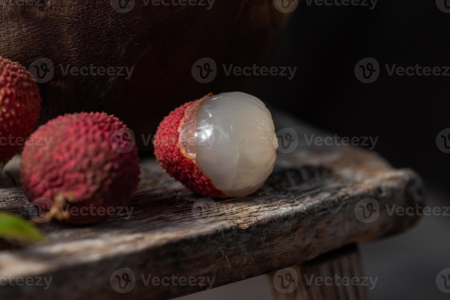 El litchi se coloca en un plato de madera, pelado o sin abrir, sobre una mesa de madera oscura. foto