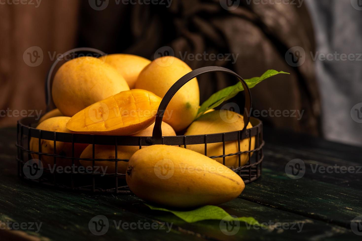 Cut and intact mangoes in the dark background photo