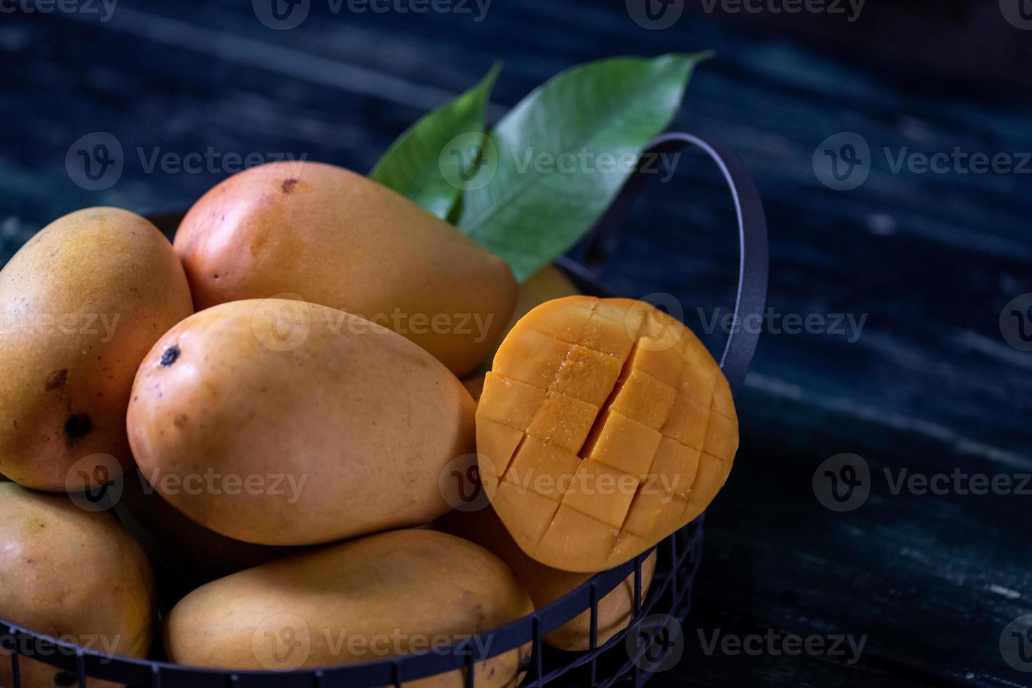 Cut and intact mangoes in the dark background photo