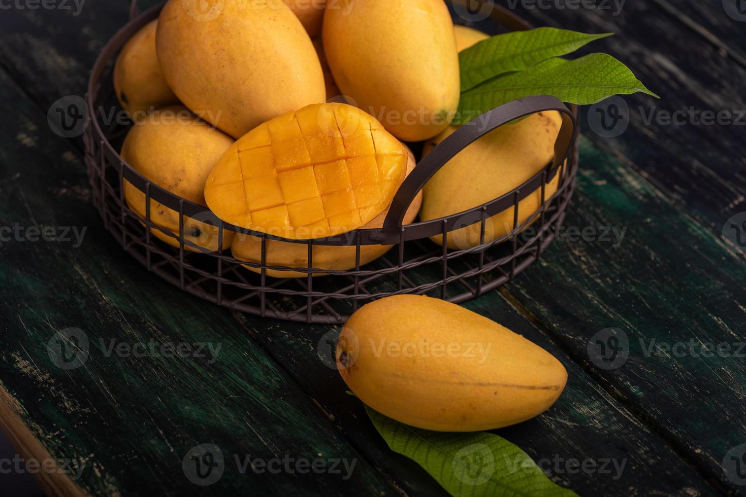 Cut and intact mangoes in the dark background photo