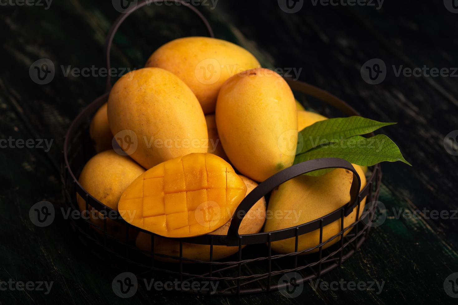 Cut and intact mangoes in the dark background photo