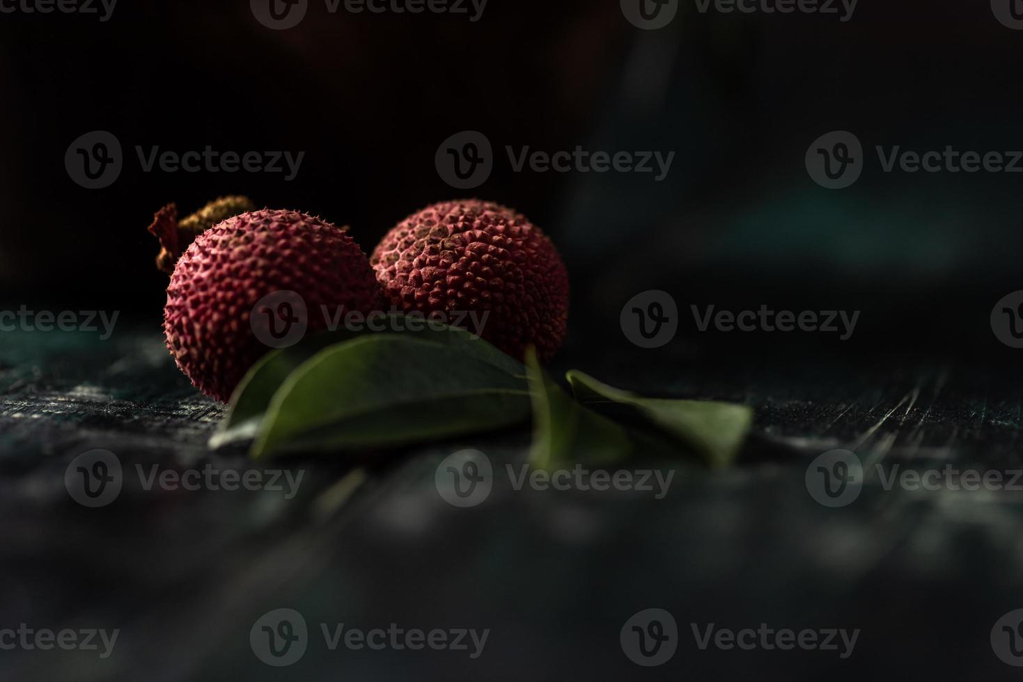 El litchi se coloca en un plato de madera, pelado o sin abrir, sobre una mesa de madera oscura. foto