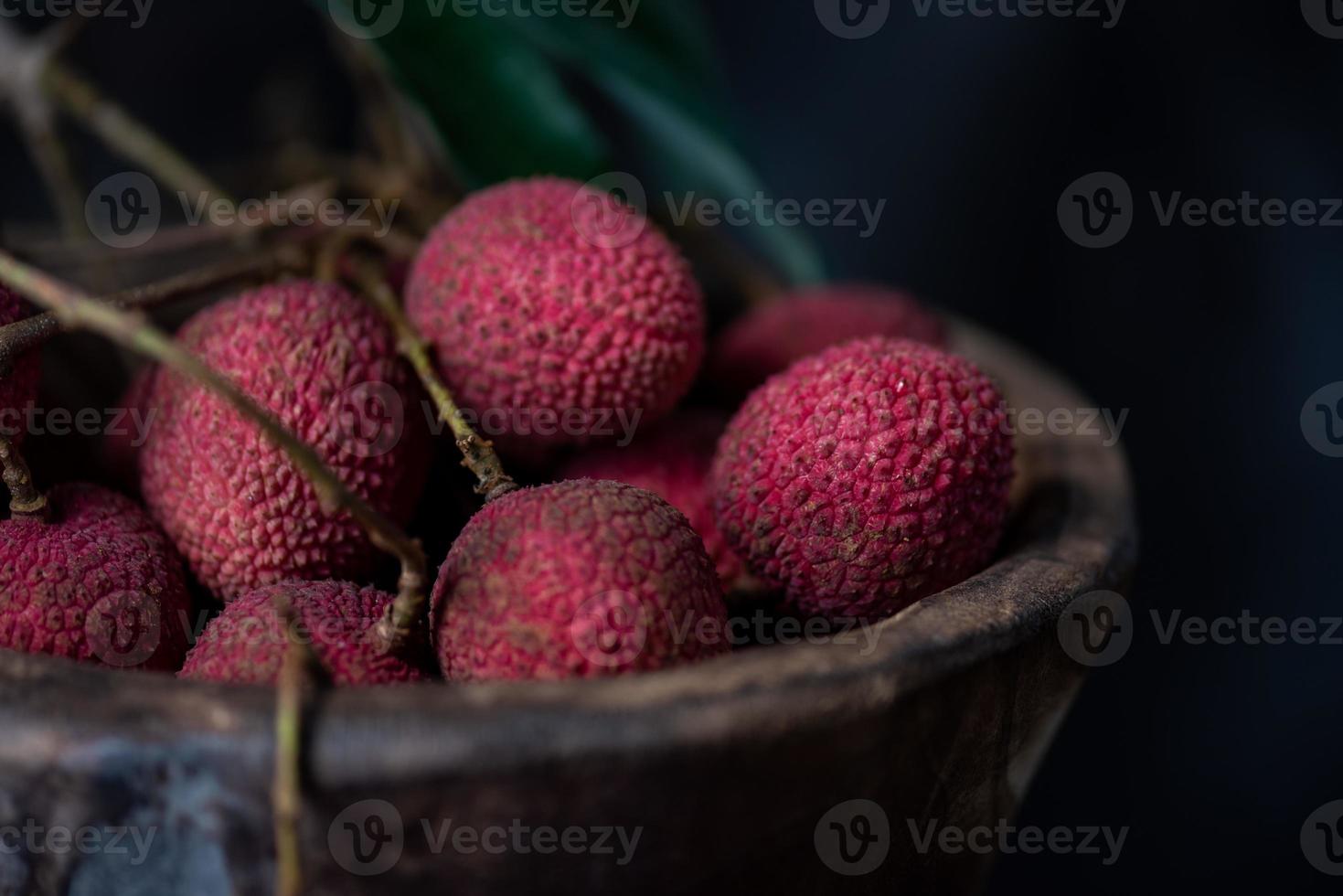 Litchi is placed in a wooden plate, peeled or unopened, on a dark wood grain table photo