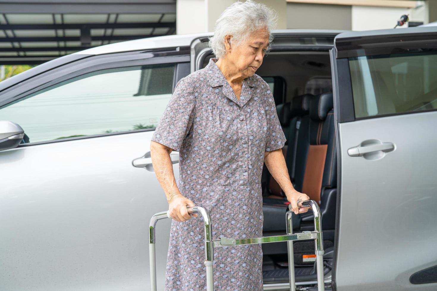 Asian senior or elderly old lady woman patient walk with walker prepare get to her car, healthy strong medical concept photo