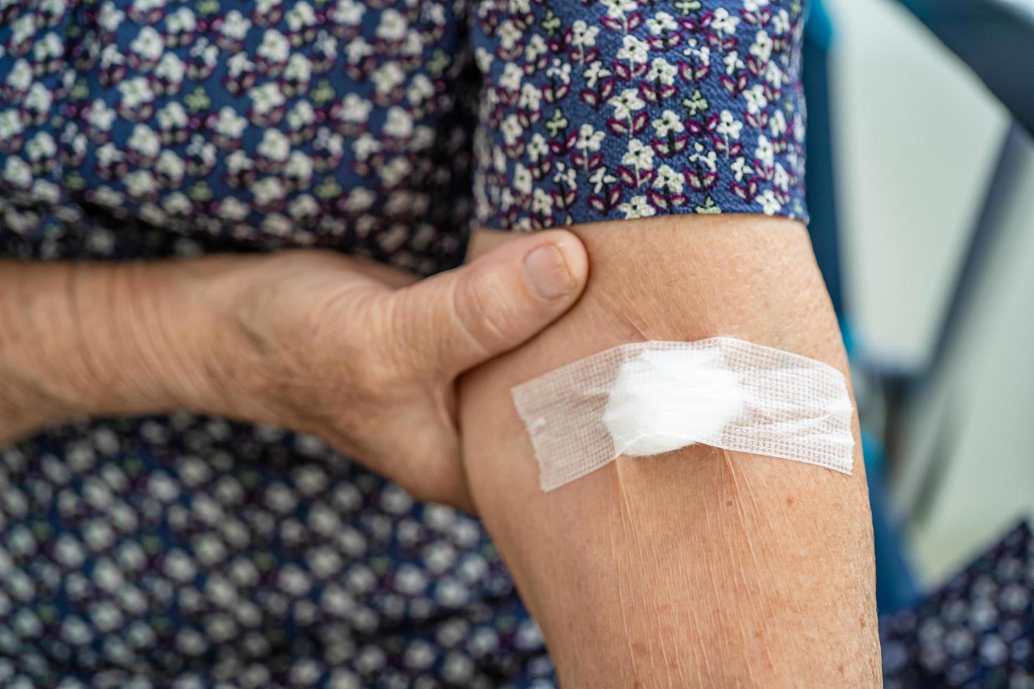 Asian senior or elderly old lady woman patient show cotton wool stop bleeding, after blood drawing testing for annually physical health check up to check cholesterol, blood pressure, and sugar level photo