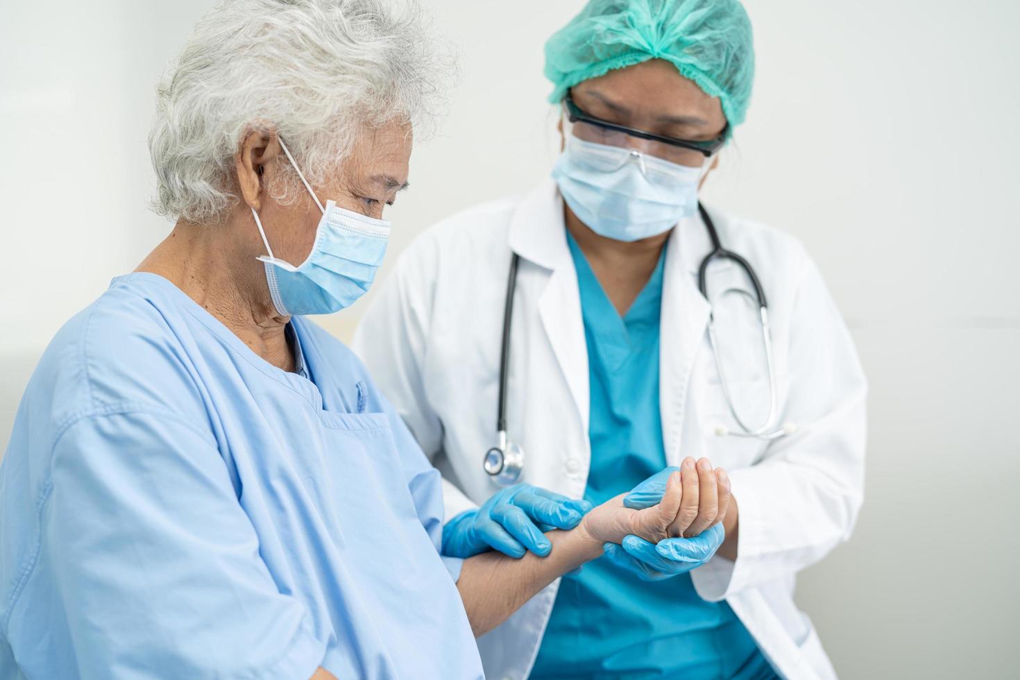 Doctor help Asian senior or elderly old lady woman patient wearing a face mask in hospital for protect safety infection and kill Covid-19 Coronavirus photo