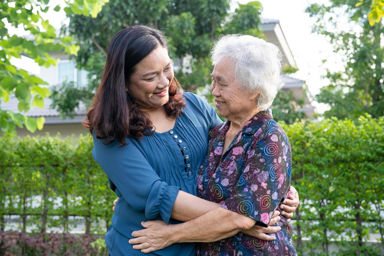 Asian elderly woman with caregiver walking help with love and happy in nature park photo