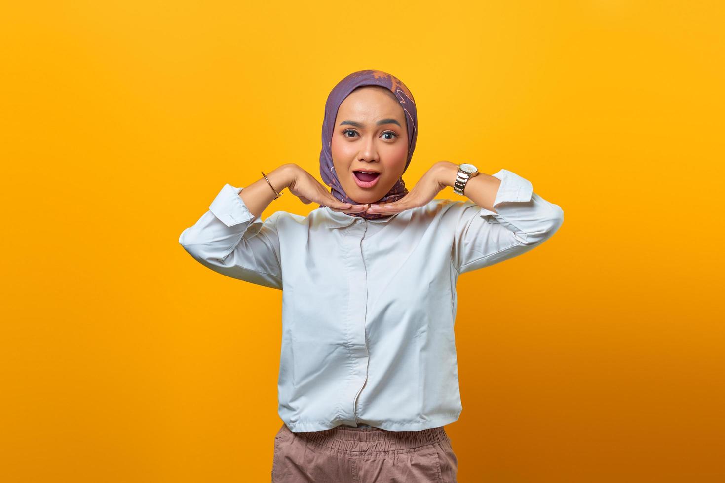 Portrait of shocked Asian woman with open mouth over yellow background photo