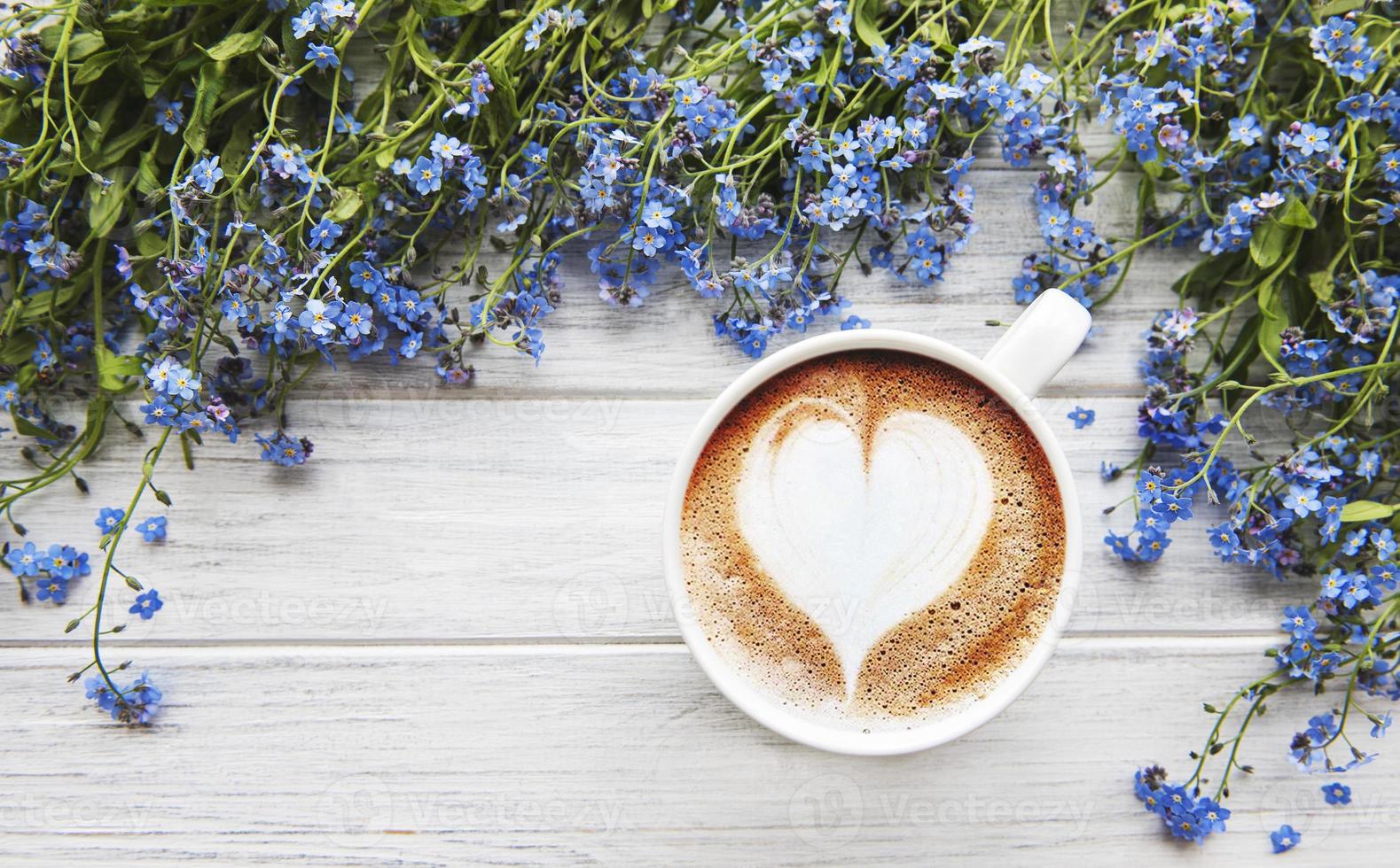 Nomeolvides flores y una taza de café sobre un fondo de madera foto