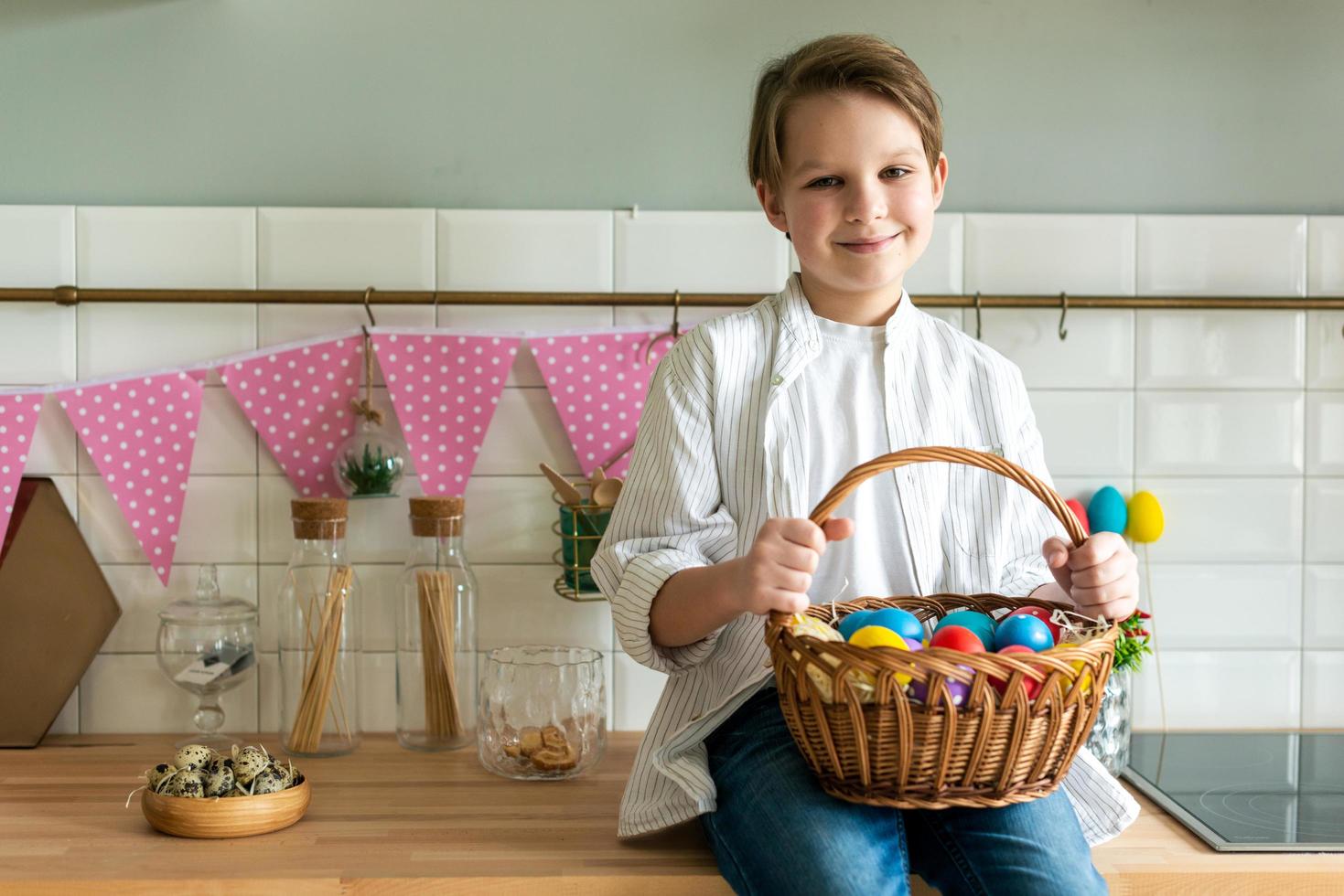 niño sonriente sosteniendo una canasta con huevos de pascua. foto