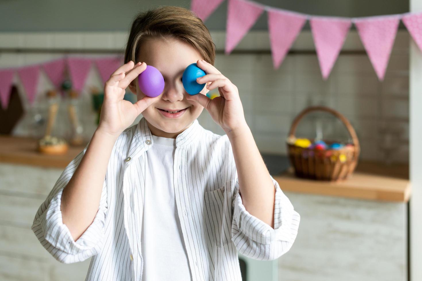 Cute little boy holding colored easter eggs instead of eyes. Happy easter . photo