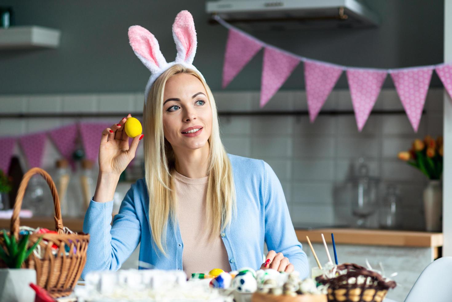 Beautiful blond woman holds an Easter egg in her hand and looks away dreamily. photo
