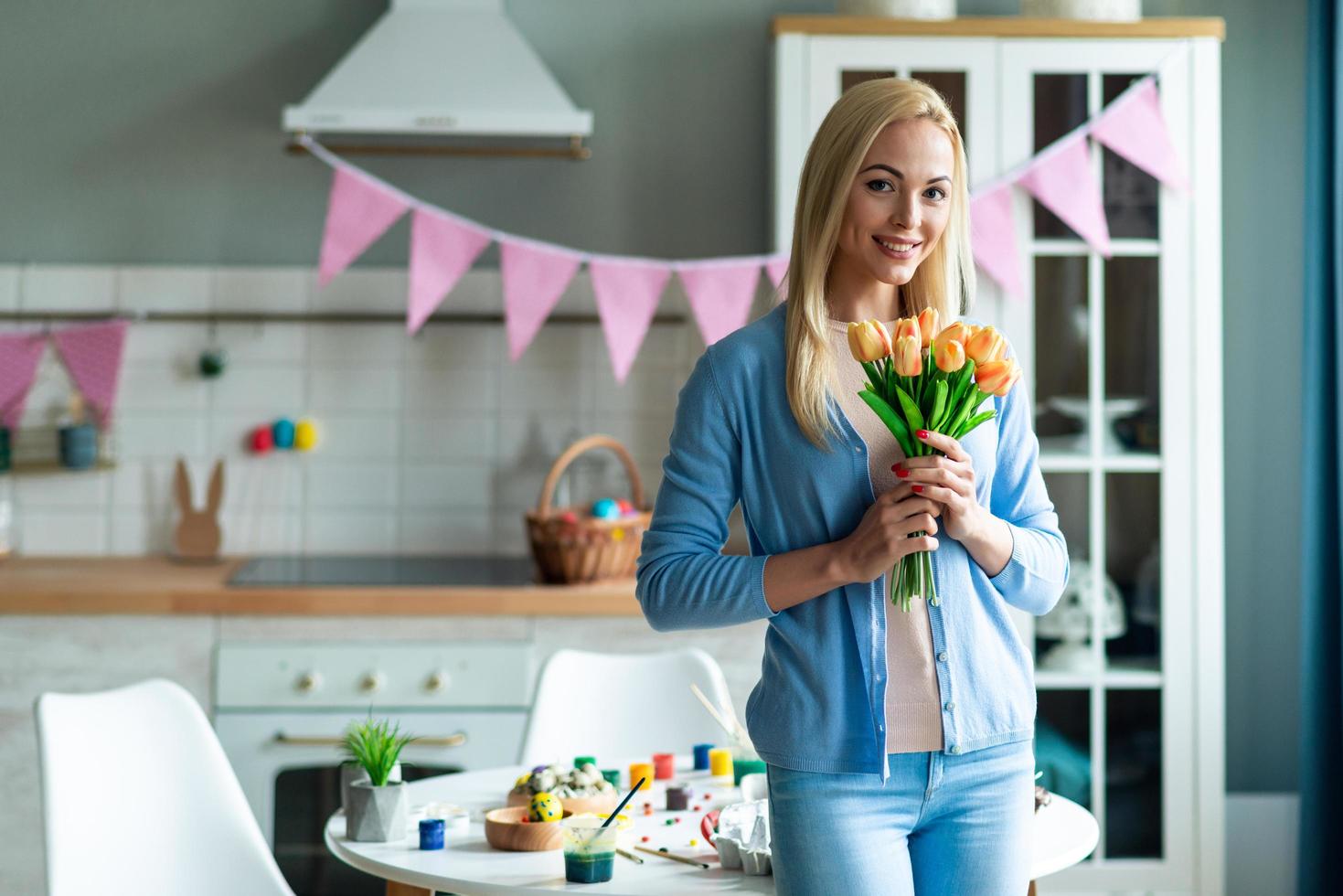 Woman holding flowers in decorated kitchen. photo
