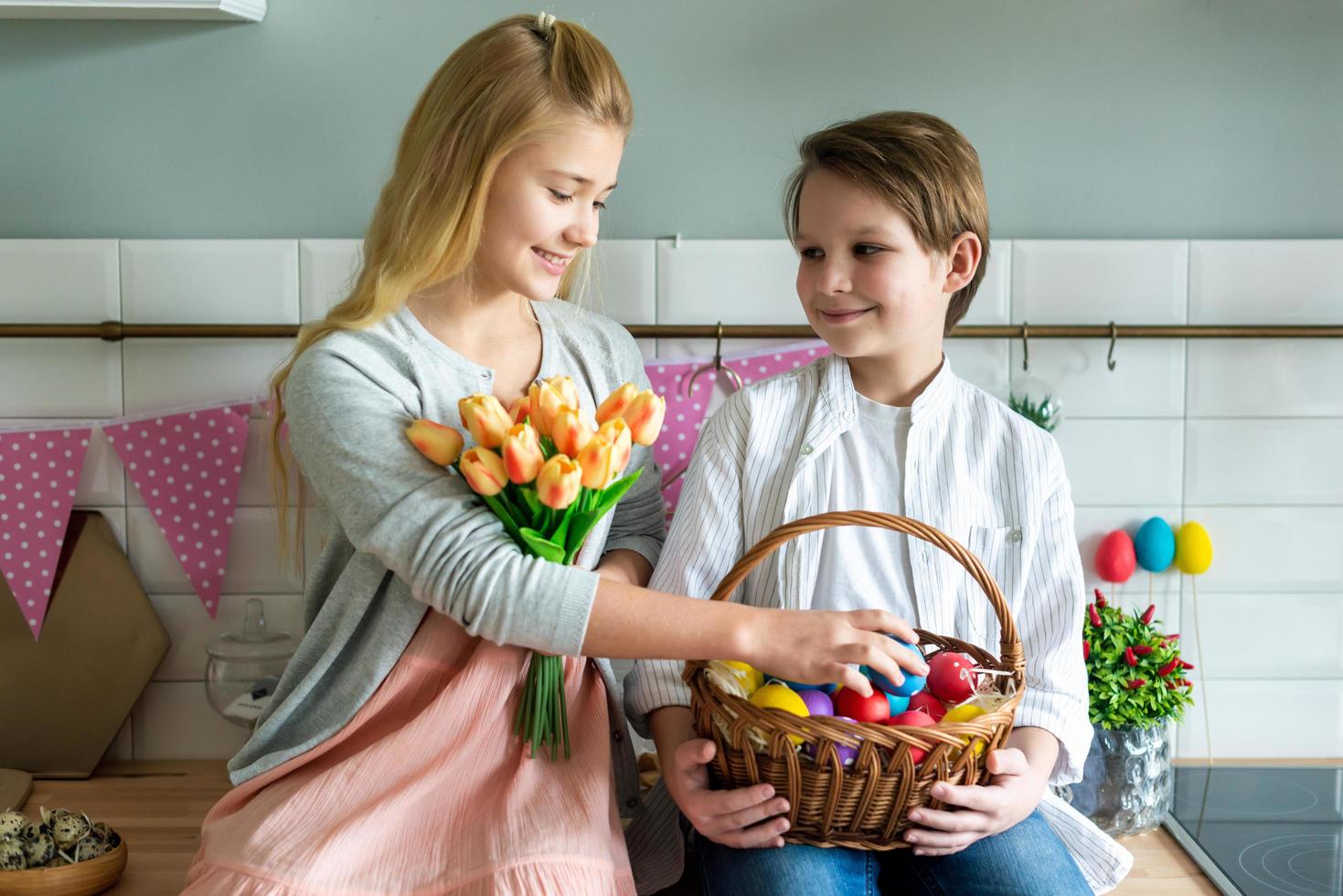 los niños juegan en la cocina y sostienen una canasta de huevos de Pascua. foto