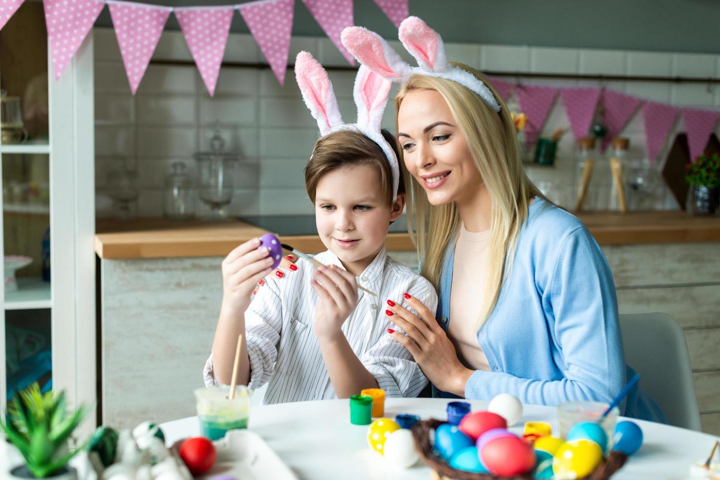 Happy mother and her cute little son paint Easter eggs together. Easter concept photo