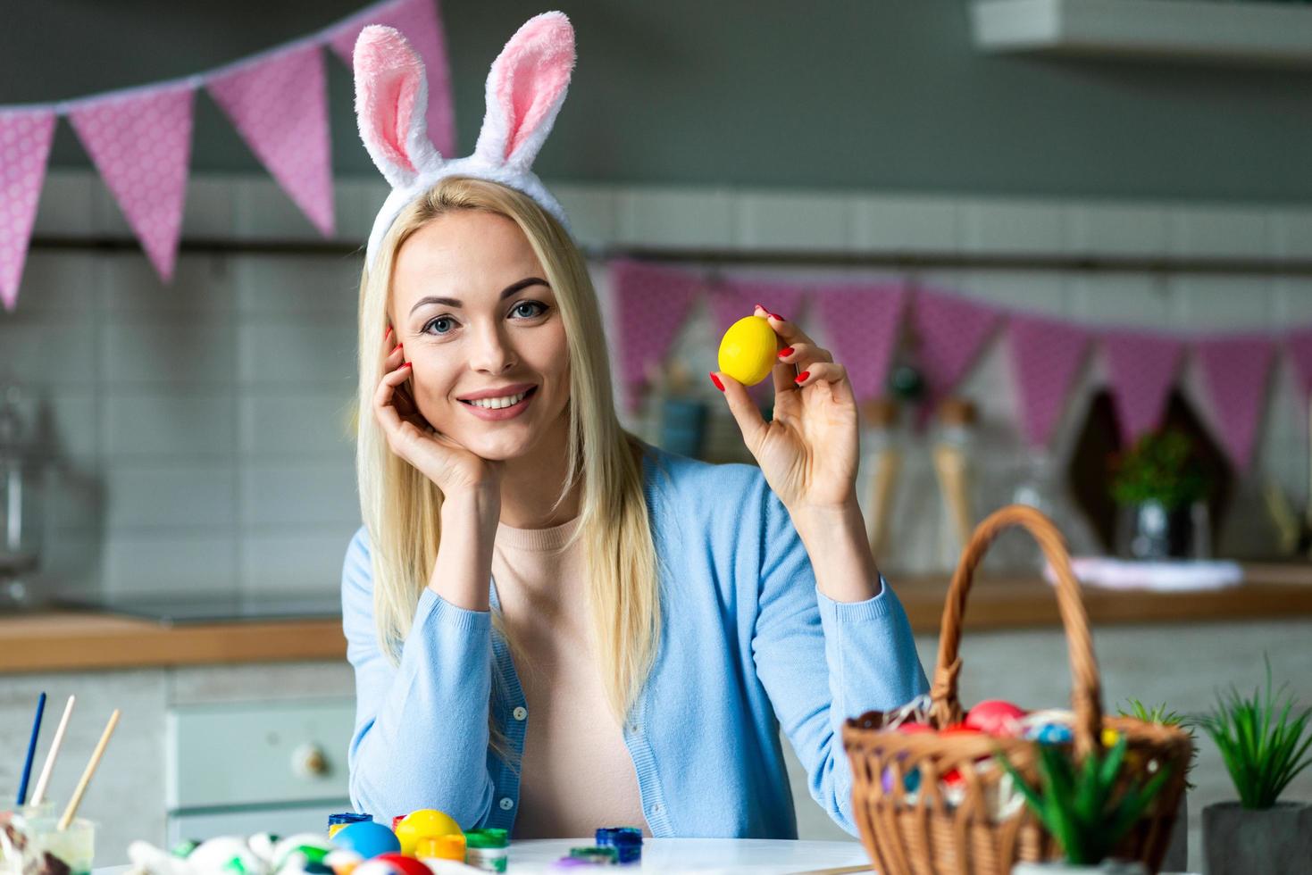 Attractive blonde puts easter eggs in Easter basket photo