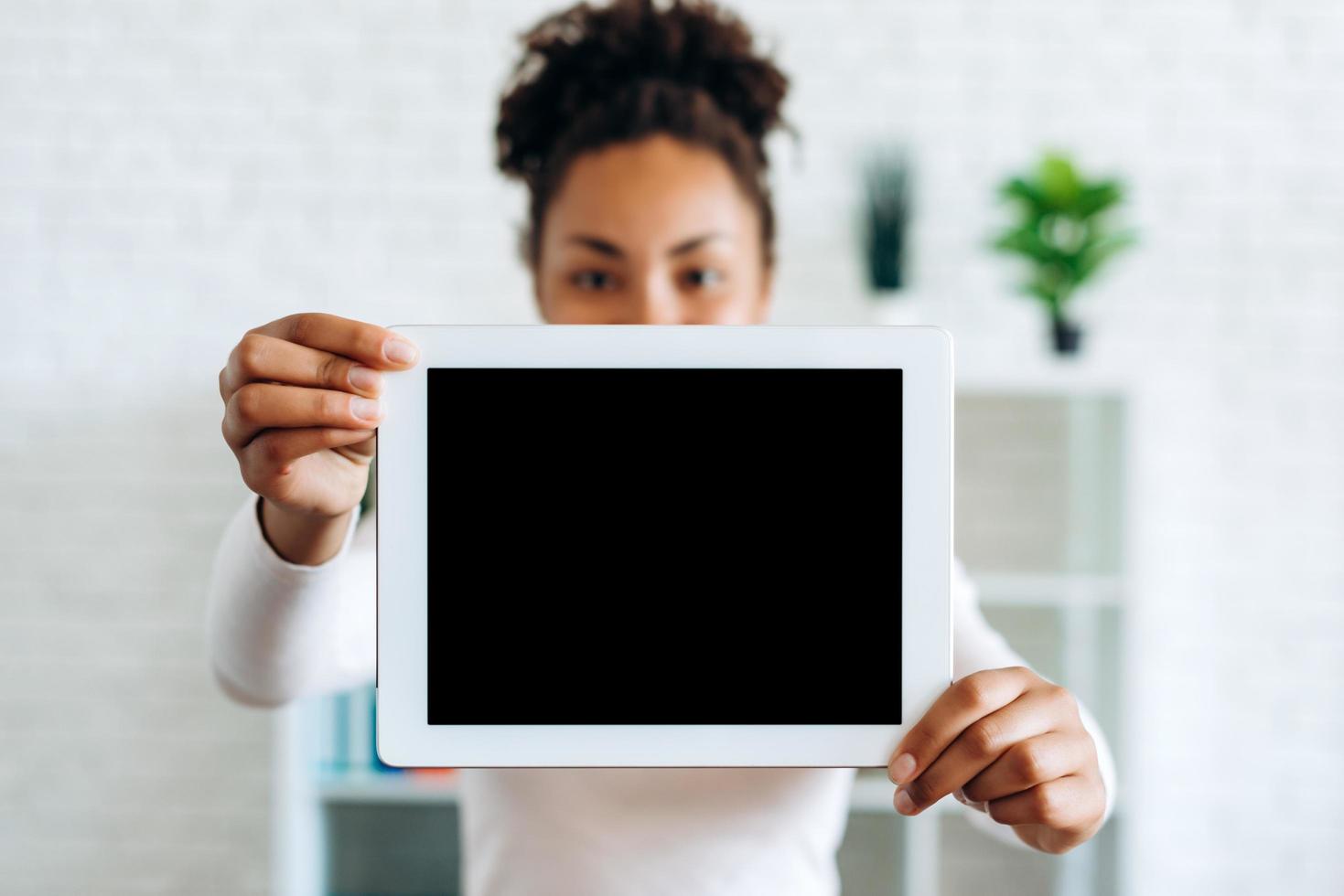 Girl holding a tablet with a blank screen on a blurred background photo