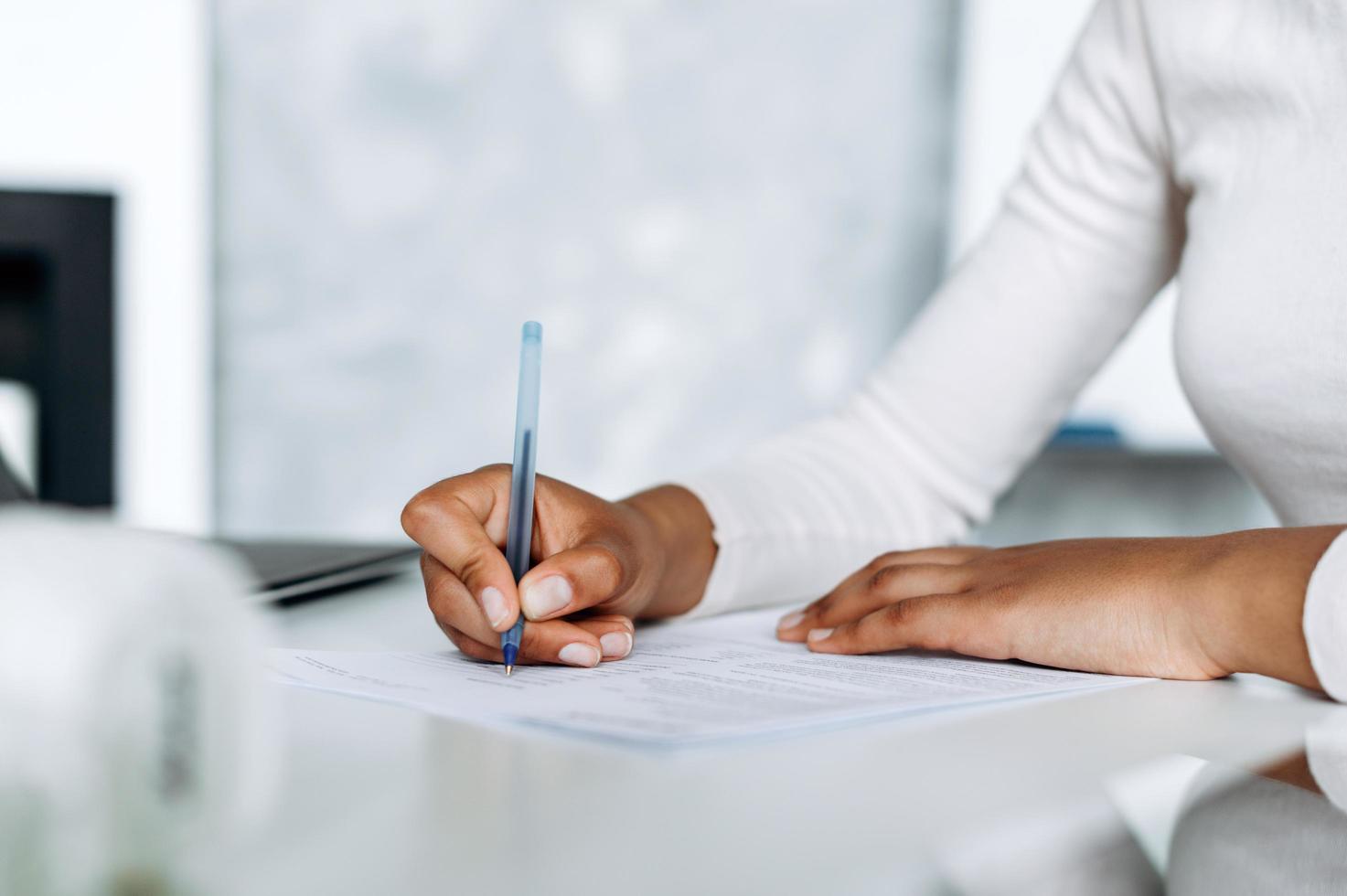 Close-up view, gentle, female hands signing documents in bright office photo