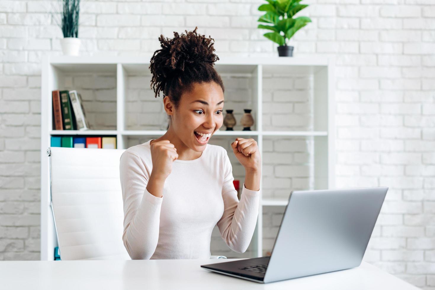 Joyful young girl working on a laptop, having completed an important task sincerely rejoices in his victory photo