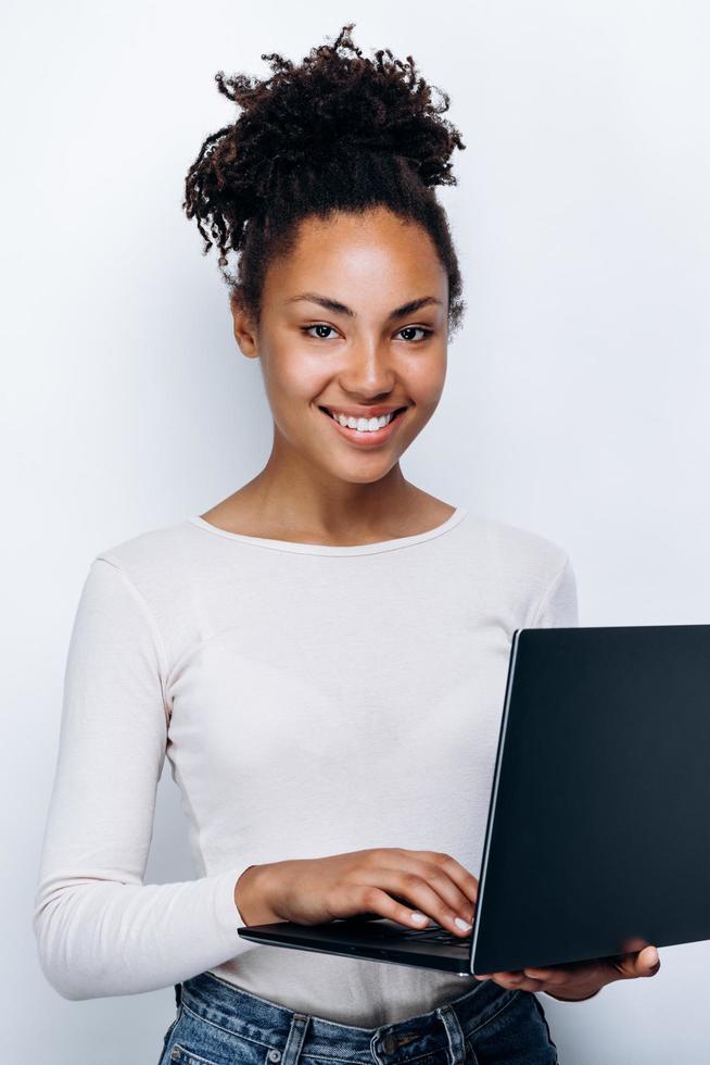 Girl with a laptop in her hands posing against a white wall photo