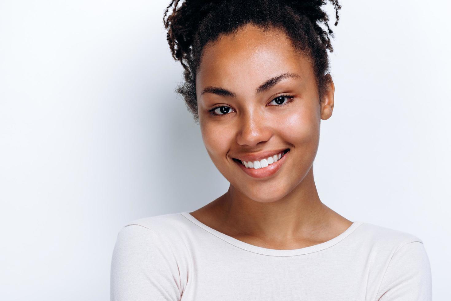 Attractive young girl posing on a white wall background, cute smiling photo