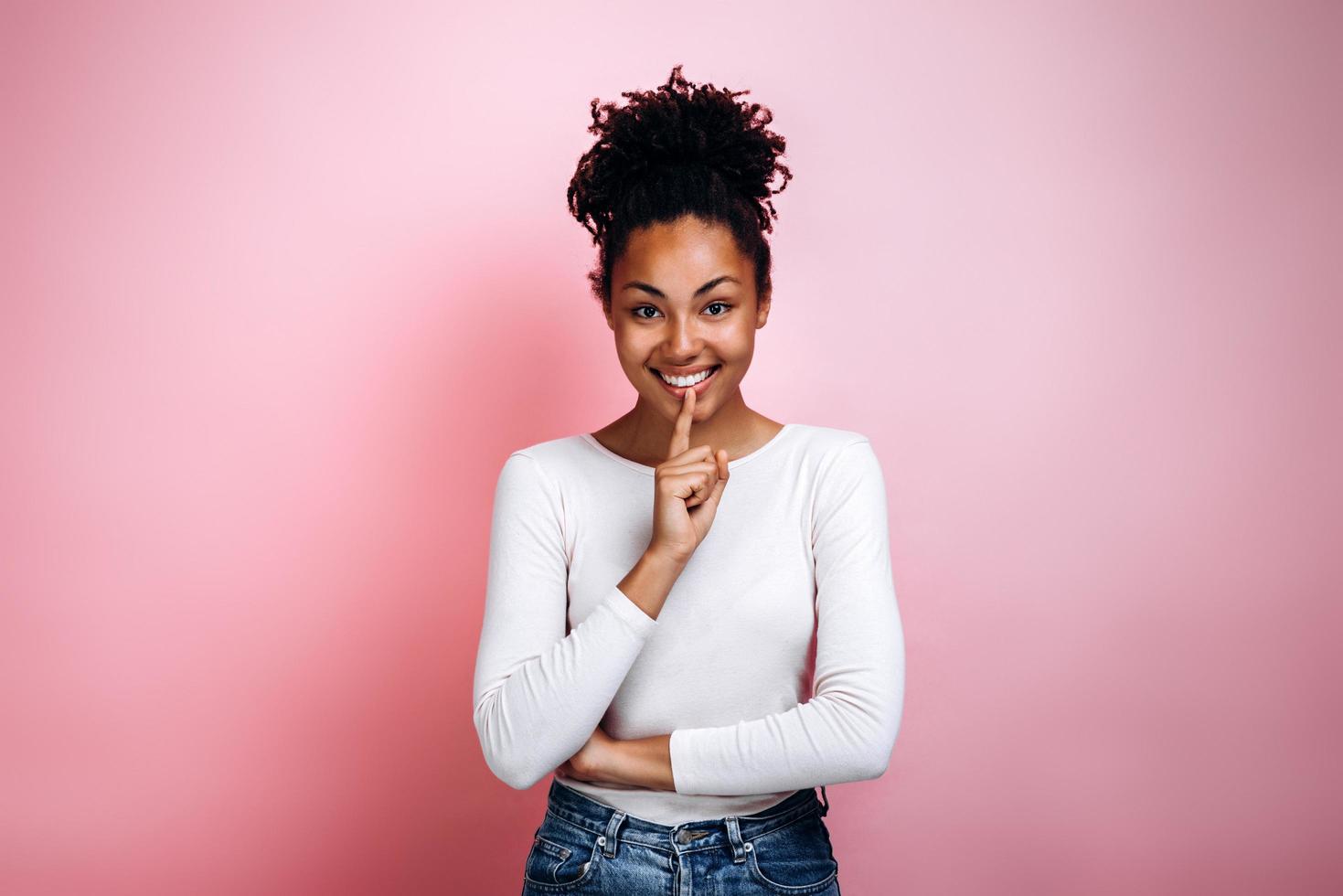 Young woman with finger showing hush silence sign, gesture and beauty concept, pink background, nice girl asking for silence photo