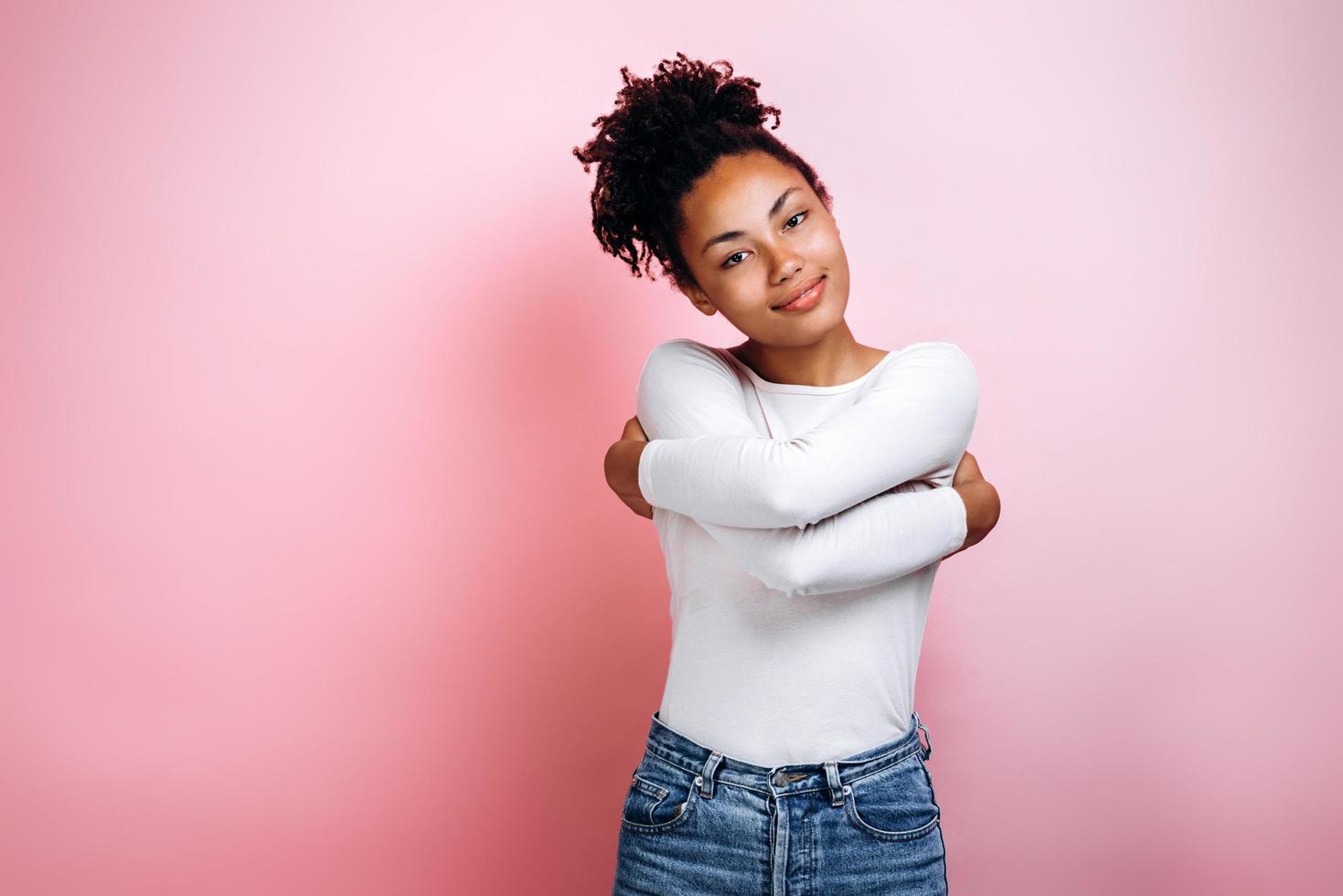 Portrait of a pretty young girl hugging, standing isolated on pink background photo