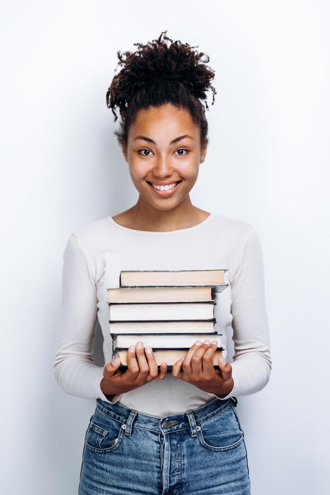 Female student holding books in studio, on white wall background photo