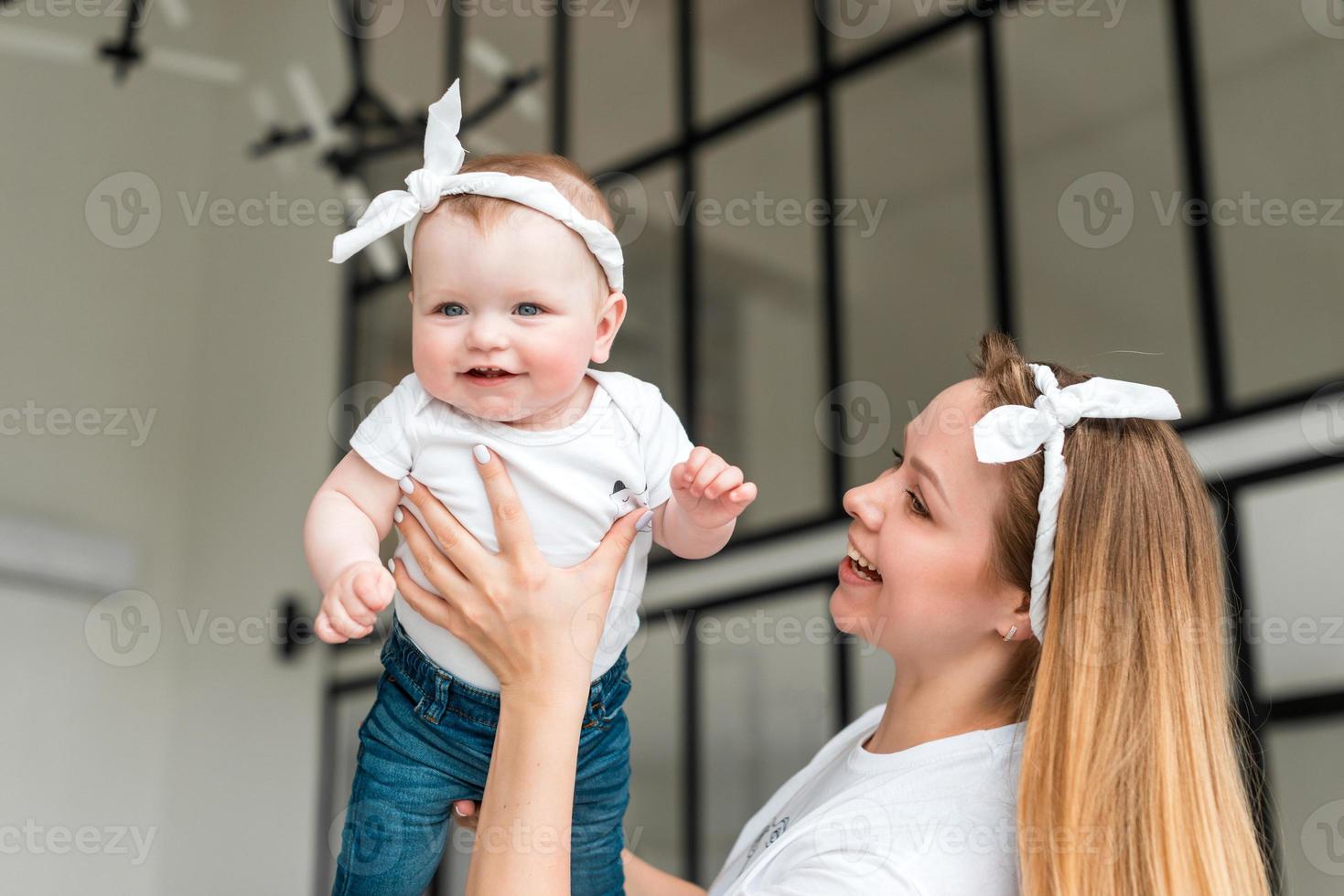 una mujer joven y bonita cría a su pequeña hija. niña sonriendo feliz foto