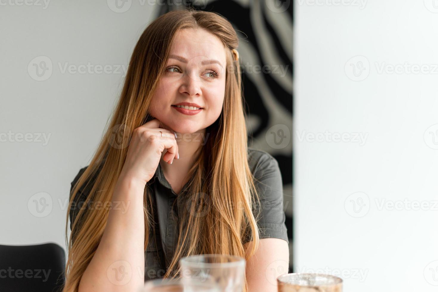 una chica hermosa y atractiva está sentada a la mesa, descansando, soñando con algo foto