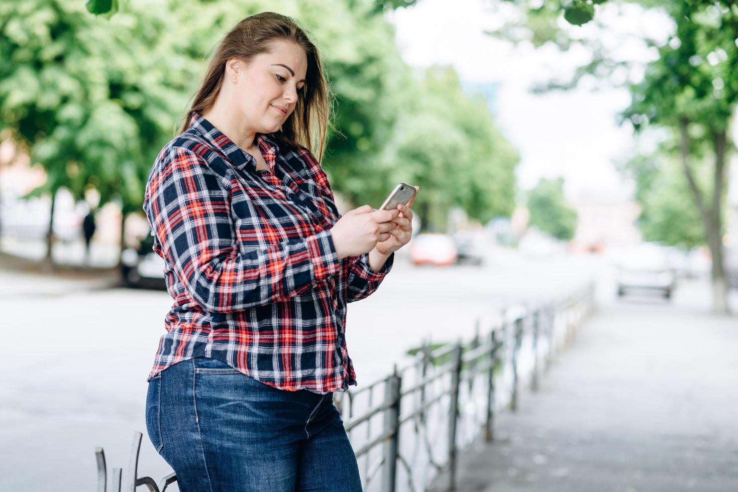 Charming, smiling girl leaning on the fence, correspond with someone on the phone photo